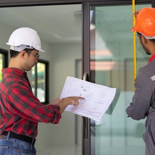 Contractor and technician measuring glass door panels for home renovation.